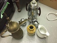 Photo of collection including metal samovar, brass pitcher, ceramic cream and sugar dish, ceramic jug, and metal water pitcher.