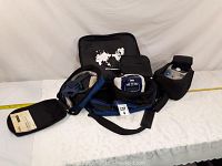 Various items including Resmed branded black carry bag, black pouch with world map graphic, headgear strap, equipment cover bag, and small accessory pouch displayed on white surface.