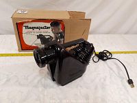 Photo of vintage black Magnajector slide projector with original cardboard box and attached electrical cord.