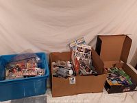 Photo showing three containers filled with assorted sports trading cards and memorabilia including loose cards, cards in sleeves, and collectible baseballs.
