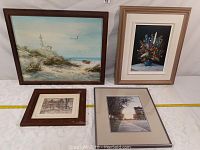 Four framed artworks displayed together on a table with measurement tape showing approximate size