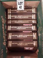 Six hardcover volumes of Matthew Henry's Commentary arranged in a cardboard box, showing the titles on their spines.