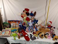 Wide shot of all Disney character items including plush toys, puzzles, and wooden cutouts arranged on a table with a white backdrop.