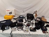 Wide view of entire camera lot with cameras, cases, boxes, and accessories spread on a surface