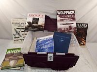 Books arranged around a plastic bin, cover titles visible including 'Combat Aircraft of World War II 1933-1937', 'Cockpits of the Cold War', 'Wolfpack', 'Planes', 'British Aircraft' and others.