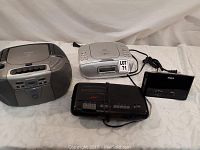 Four boombox radios including cassette decks and CD players, varying in size and color.