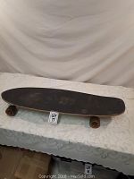 Full top side view of used black skateboard deck on a table.