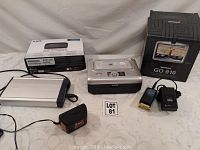 Kodak photo printer, TomTom GO 910 GPS device with charger and box, external hard drive enclosure, small black adapter, D-Link Mobile Wireless 3G Router box