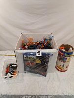 Overall view of the lot showing a large box of K'Nex pieces, a small white basket of wheels and parts, and a Tinkertoy container.