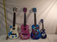 Full shot of all four guitars lined up showing various decorative designs and size differences.