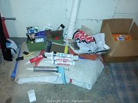 Photo taken to show all items together, including moving blankets, paint brushes, caulk tubes, paint tray, caulking gun, and box with painting supplies.