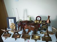 Wide view of all lot items including brass stocking hangers, wooden elephants, candle holders, figurines, and clock on a flat surface.