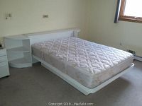 Full view of the white laminate full size bed frame with mattress on top, showing the overall setup and side shelves.