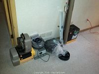 Vintage slide projectors and DaLite retractable projection screen positioned in room on carpet floor, showing grouping of projectors, cords, and screen tripod.