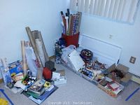 Corner area showing multiple rolls of project paper, wrapping paper, and craft materials assembled on the floor and buckets