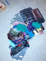 Overview photo showing assortment of scarves in multiple colors and patterns along with grey plastic scarf holders with hooks.