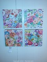 Full view of all four 12x12 watercolor floral paintings hung on a wall.
