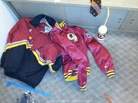 Two Washington Redskins jackets laid on floor with water bottle nearby