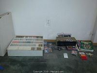 Wide view of five trays filled with baseball cards and additional small stacks of cards on the floor.