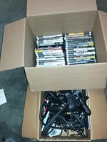 Photo of a box containing a large selection of PlayStation 2 game cases stacked upright showing spines.