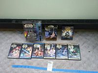 Full view of the lot including all six Episodes of Star Wars DVDs in cases, a Clone Wars DVD, and the collector timepiece in original packaging.