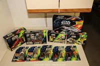 Photo showing full lot of Star Wars collectibles in their boxes on table including figures and vehicles.