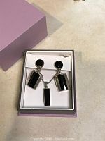 Photo showing sterling silver necklace and matching earrings with black onyx stones arranged in a presentation box with lavender exterior.