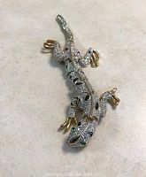 Front view of the large articulated lizard/gecko brooch with rhinestones and gold-tone toes, showing detailed body and rhinestone placement.