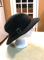 Side view of the extra large black wool tweed winter Tilley hat showing wide brim and buckle detail.