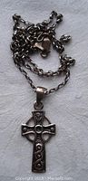 Photo of Celtic cross pendant hanging flat showing intricate design details and "925" marking