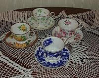 Four vintage tea cups and saucers displayed on lace tablecloth showing original patterns and colors.