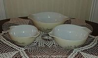 Three Pyrex Cinderella nesting bowls arranged side by side showing size difference and pattern on exterior sides.