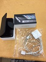 Apple iPhone 4 in black flip case shown partially open on original box with charging cable.