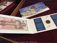 Canadian 1986 two dollar bill and 1996 Toonie coin mint set in presentation folder with polar bear cover and Arctic paw prints.