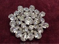 Close-up view of the vintage Weiss brooch showing clear rhinestones arranged densely in round and teardrop shapes on a silver-tone base.