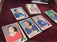 Stack and some loose hockey cards on a table showing player images and team logos.