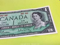 Close-up image of the front side of the 1967 Canadian one dollar banknote under good lighting showing the overall note design clearly with the image of Queen Elizabeth II and centennial text.
