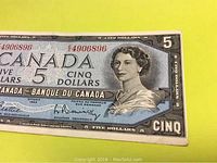Front side of 1954 Canadian five dollar banknote showing Queen Elizabeth II portrait, serial number, and signatures.