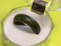 Photo showing side view of a dark green pure jade ring in a clear display box with white cushion.