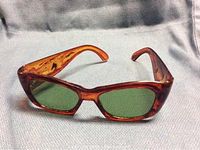 Front view of mid-century tortoiseshell sunglasses with green lenses.
