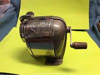 Front side view showing the brand Boston and self feeder model number 4, along with the shiny cast metal body and hand crank.