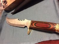 Side view of the full blade and wooden handle with gold-tone guard, showing the knife's size and shape.