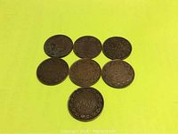 Seven Canada large cent pennies laid out on yellow background showing reverse sides with clear dates and maple leaf design.