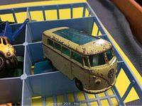 Close-up of a yellow-green Volkswagen-style van with visible paint wear showing condition of toy vehicles.