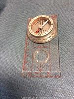 Top view of pocket-sized compass on a transparent base showing degree markings and cardinal directions
