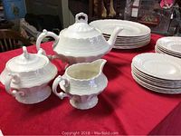 Full lot view showing teapot, sugar bowl, creamer, and two stacks of plates on red tablecloth