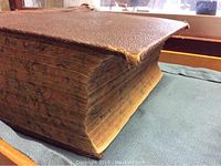 View of the thick, large brown textured cover of the vintage medical book showing wear and detached spine corner.