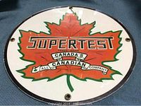 Full view of the round plastic sign showing the Supertest logo and maple leaf design.
