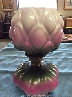 Front view of assembled lamp on blue cloth showing artichoke pattern and coloration.