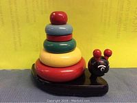 Full view of the wooden toy snail showing its colorful stackable rings and snail-shaped base.